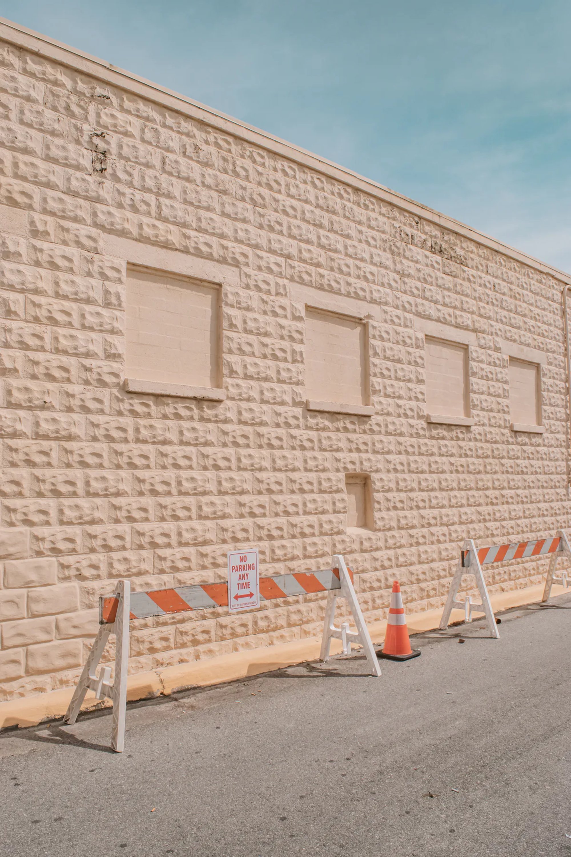 Long white block wall lined with road barricades and orange cones.