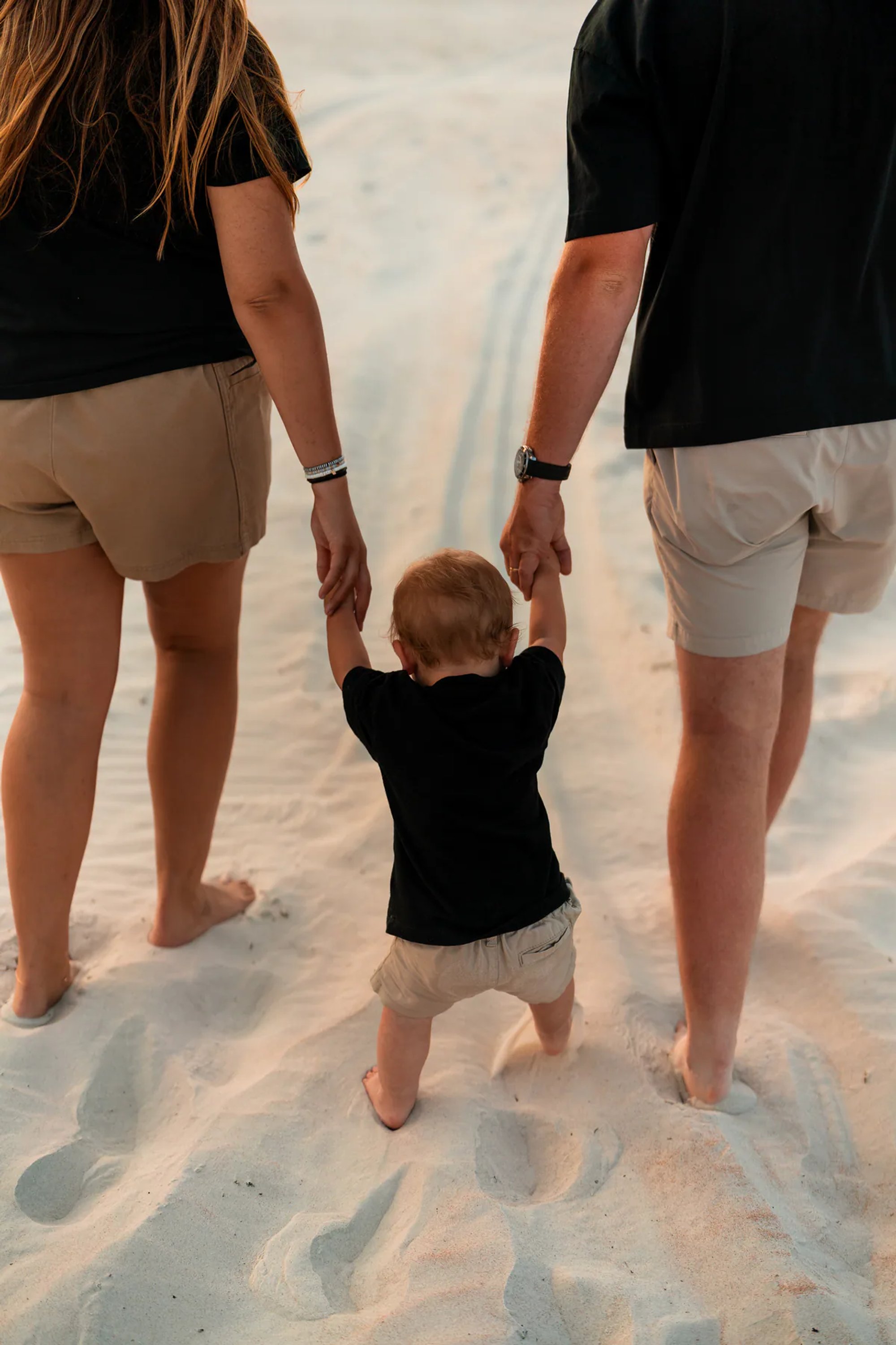Parents walking with their toddler on the sand during a Ponce Inlet Beach family photo session.