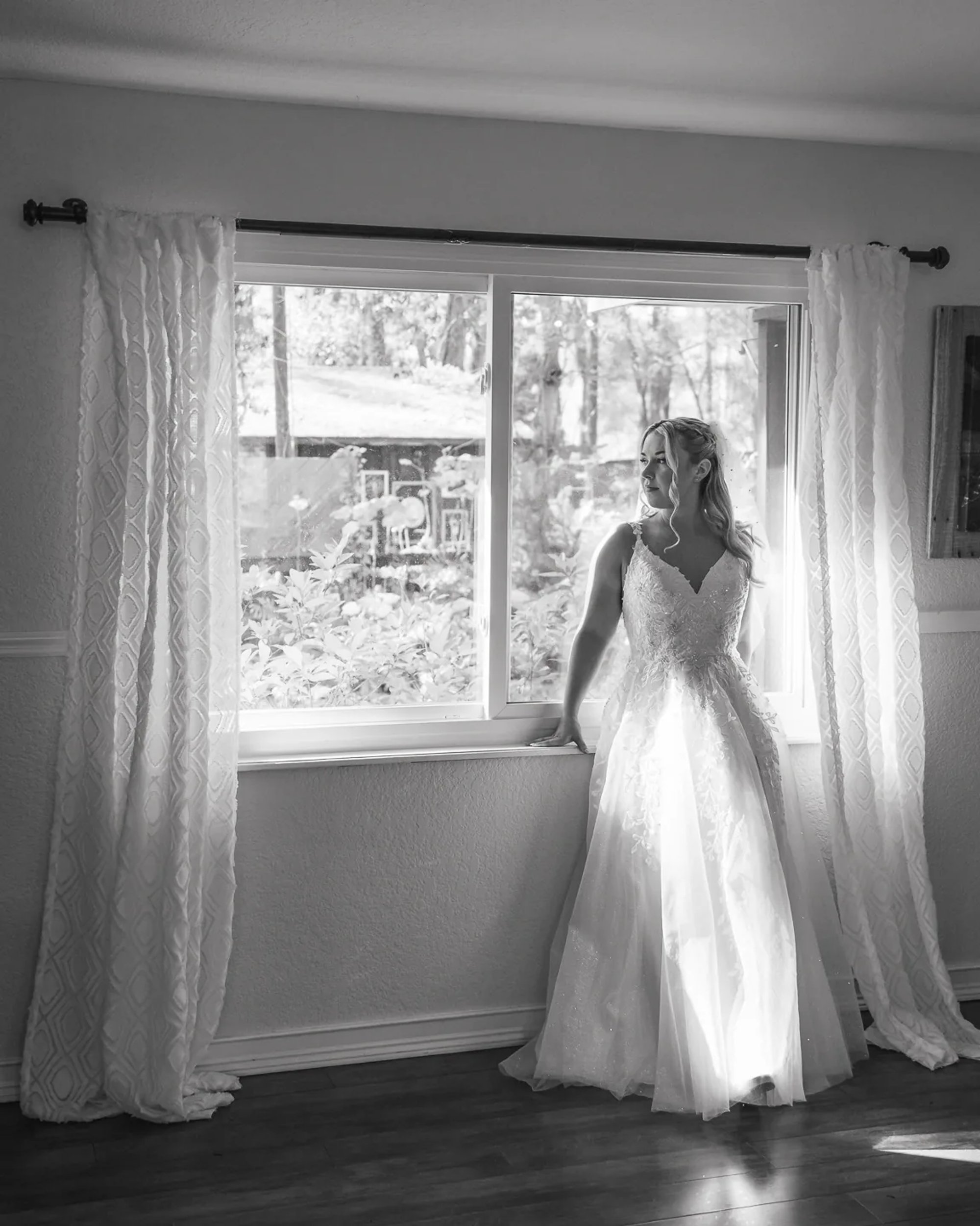 Bride standing by window in wedding dress at Bridle Oaks Barn in DeLand Florida