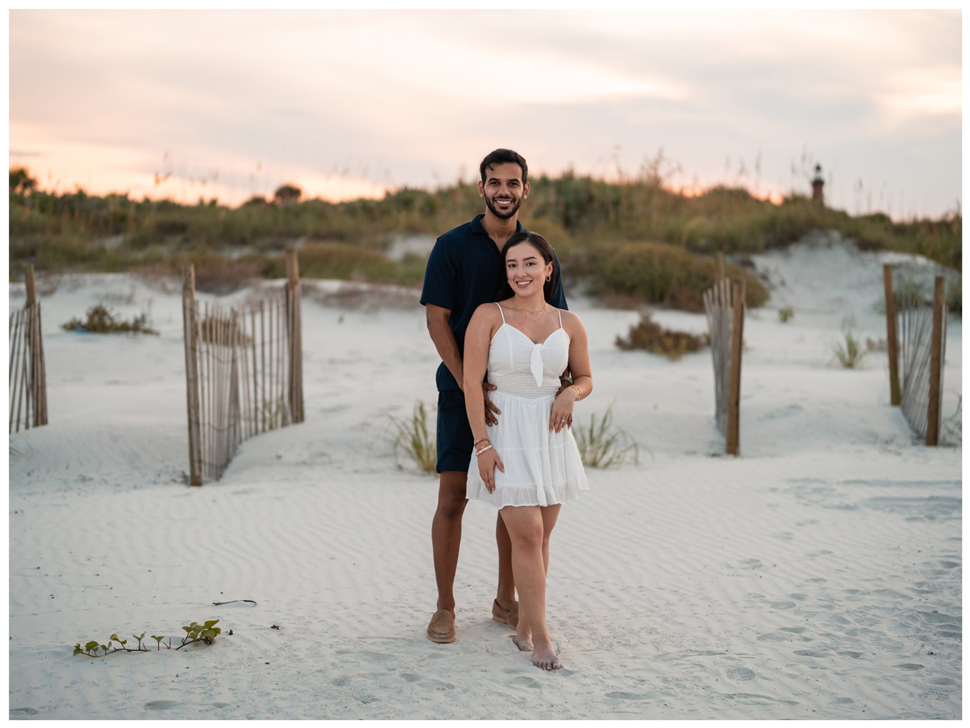 Dierick standing behind Paulina during their evening beach engagement portraits.