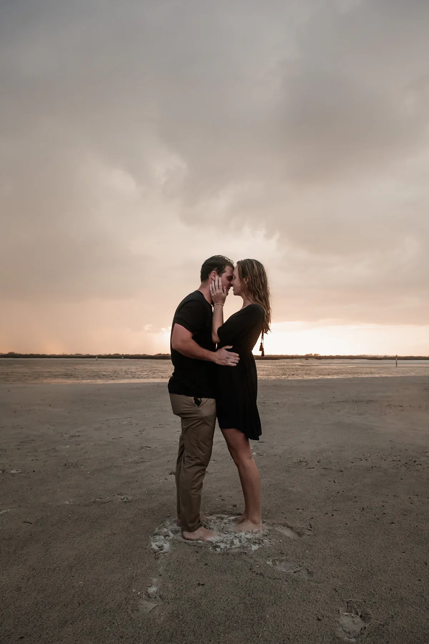 Moody Ponce Inlet engagement photo of couple standing together under storm clouds on the beach