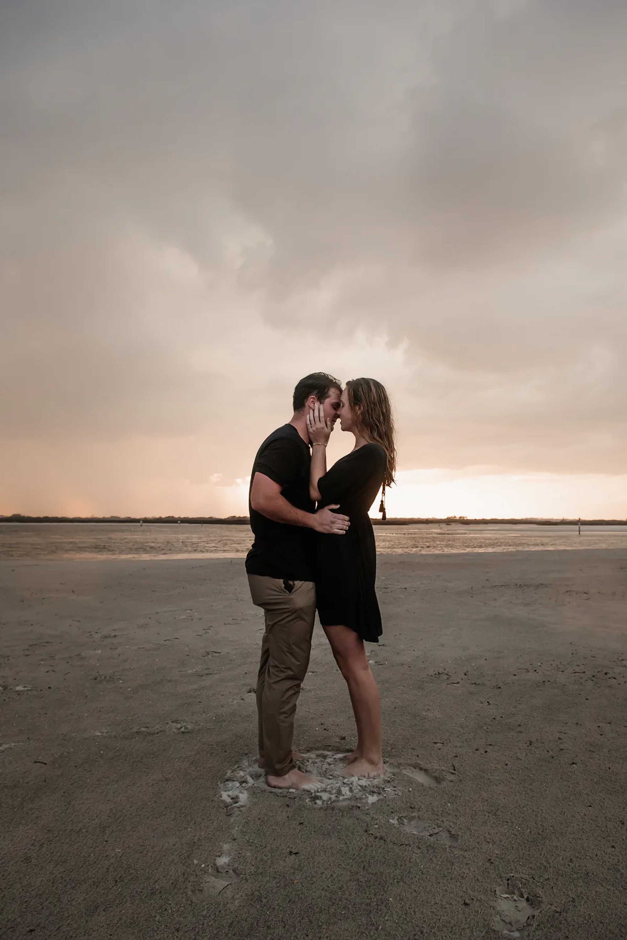 Moody Ponce Inlet engagement photo of couple standing together under storm clouds on the beach
