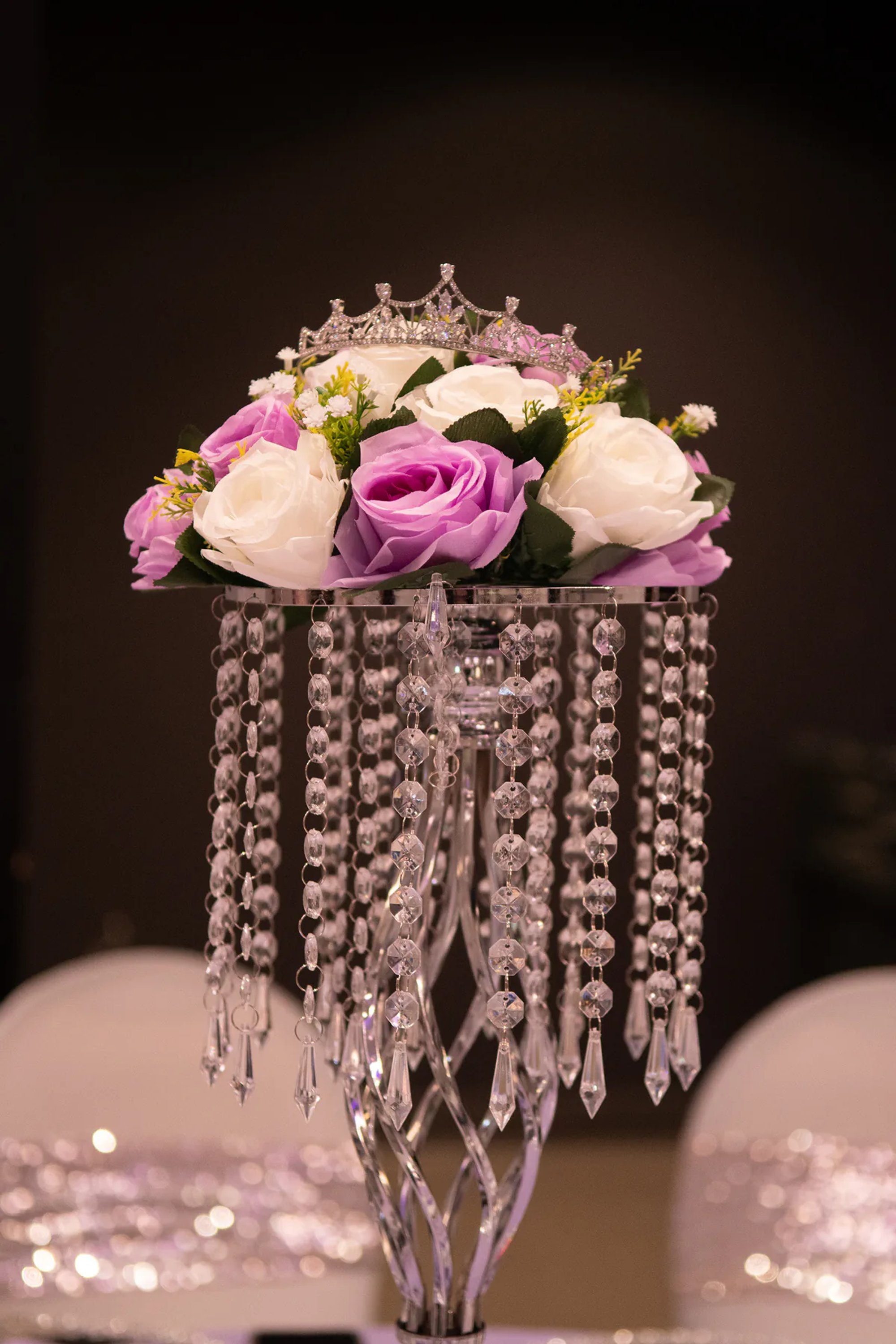 Purple-and-white floral centerpiece with hanging crystal strands.