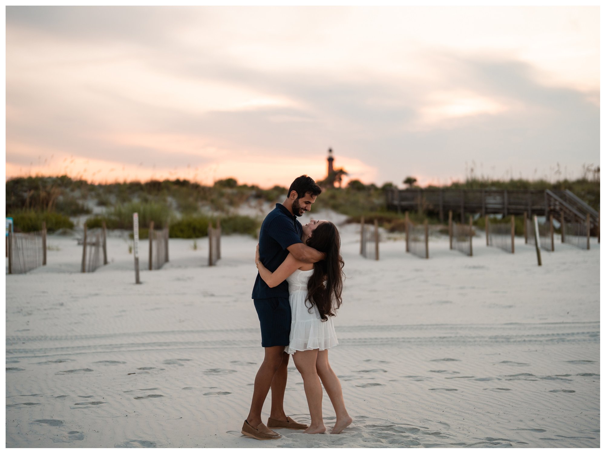 Dierick and Paulina sharing a playful embrace on the sand at Lighthouse Point Park.