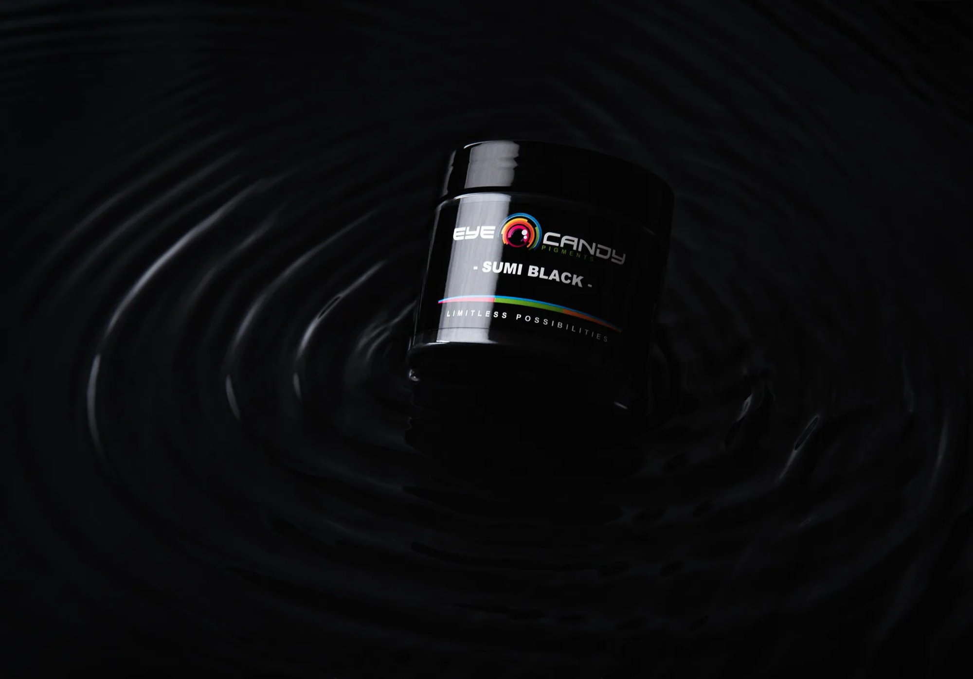 Eye Candy Pigments Bumi Black jar surrounded by ripples on a black surface.