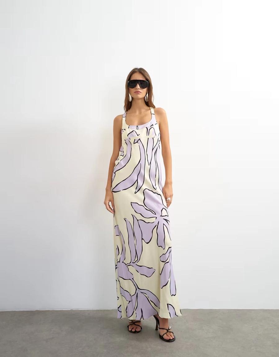 Model wearing the Satin Scoop Neck Maxi Dress by Topshop. The lilac and buttermilk floral satin dress is cut on the bias with a slim, fluid maxi silhouette that follows the body. The front features a scoop neckline with topstitched detailing and mini bra-style panelling, with a shaped bust seam adding structure through the bodice. The back is open and finished with a T-bar strap that crosses across the upper back. A hidden button fastening on the inside of the strap allows the dress to open for ease of dressing while keeping the back clean. The bias cut allows the soft satin fabric to fall naturally around the body, while the shaped seams and panelling give definition to the silhouette. Iole developed the pattern as the creative pattern cutter, working through the fit, bias cut, neckline, bust shaping and considered back fastening.