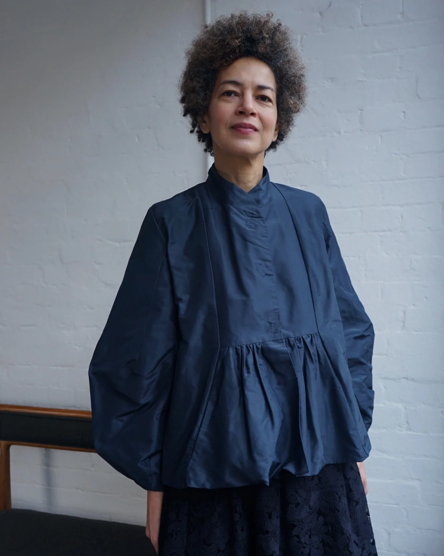 Model wearing the Alma Jacket by sustainable womenswear brand Studio Wylder. The jacket features a sculptural silhouette with a gently flared peplum, engineered sleeves, softly defined front yoke, neat mandarin collar and snap front fastening. Studio Iole developed the creative pattern through fittings and refinements, working closely on the fit, silhouette and construction through to the final sealed production pattern used to produce the finished garment shown . Graded the pattern through sizes UK6-Uk16. Made in Silk for the premium womenswear brand.