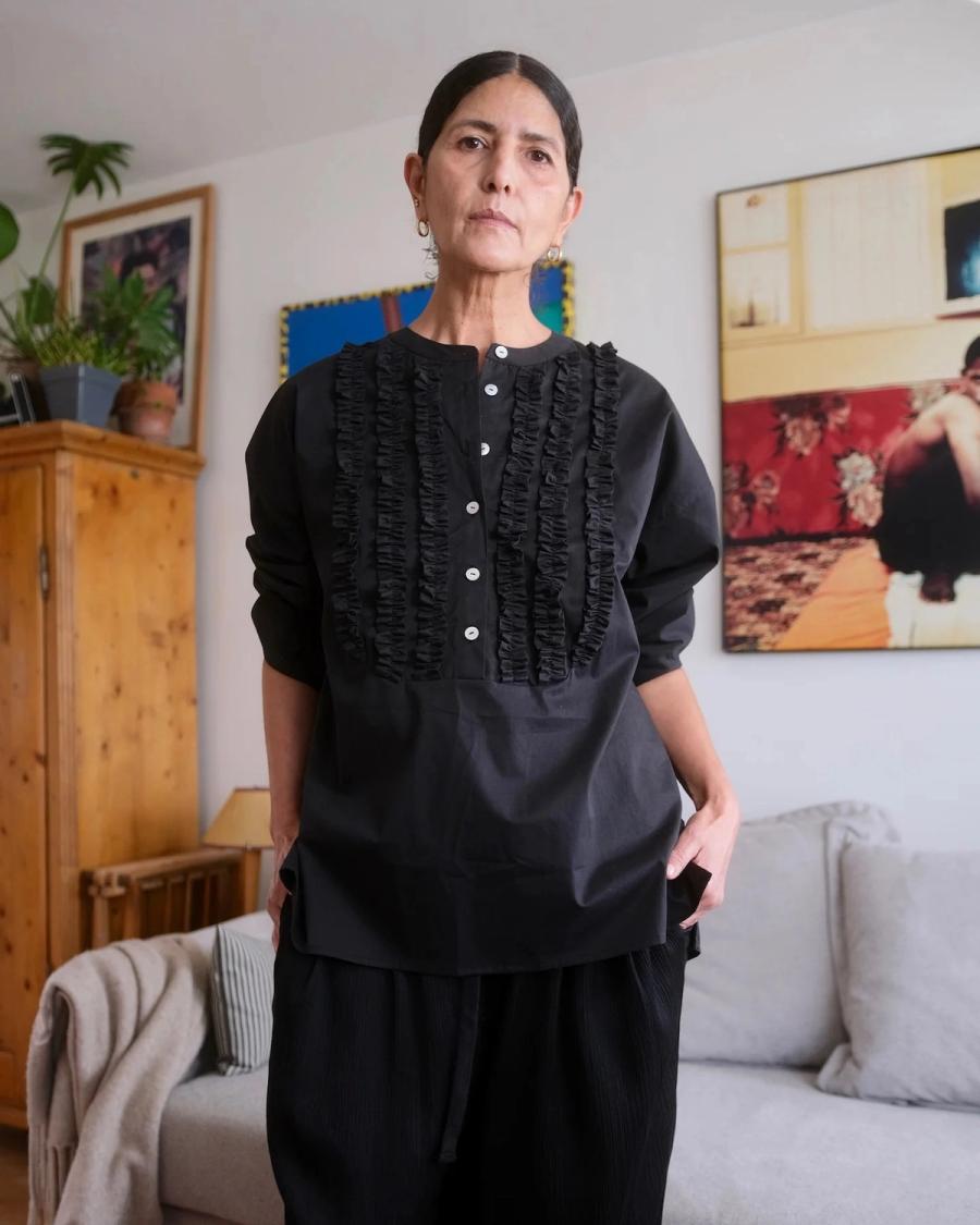 Model wearing the Ruffle Blouse by sustainable premium East London based womenswear brand Studio Wylder. The blouse features a straight, relaxed silhouette with dropped shoulders and considered ruffle detailing around the front panel and neckline, taking inspiration from formal menswear ruffle evening shirts with a modern finish. Tailored cuff detailing and mother of pearl buttons add a refined, premium touch to the design. Studio Iole developed the creative pattern through fittings and refinements, working closely on the fit, silhouette and construction through to the final sealed production pattern used to produce the finished garment shown.