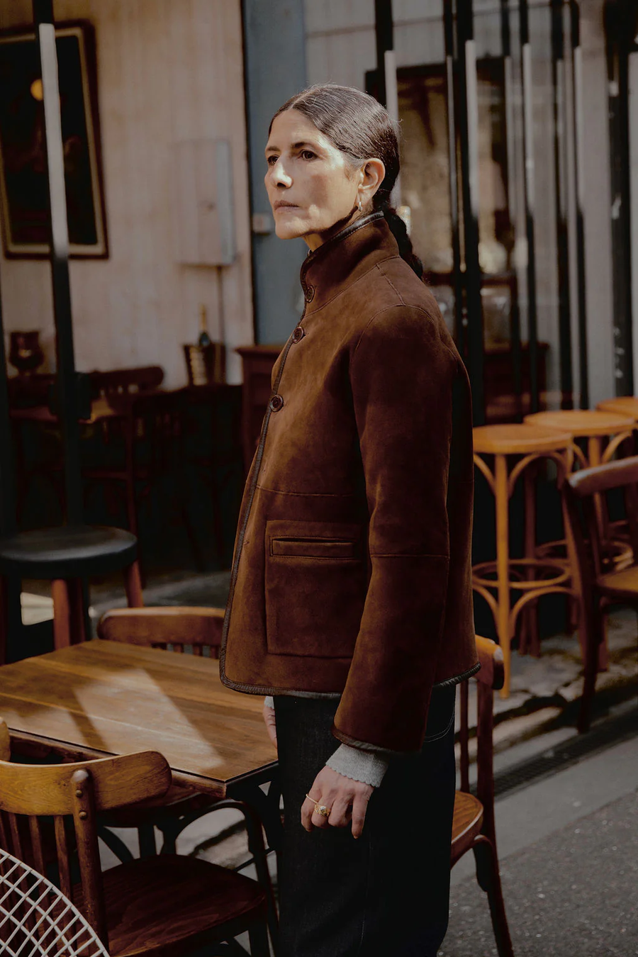 Model wearing the Carolyn reversible spring weight shearling jacket by sustainable premium womenswear brand Studio Wylder. Photographed in front of a French bistro on the streets of Paris. The jacket is crafted from 