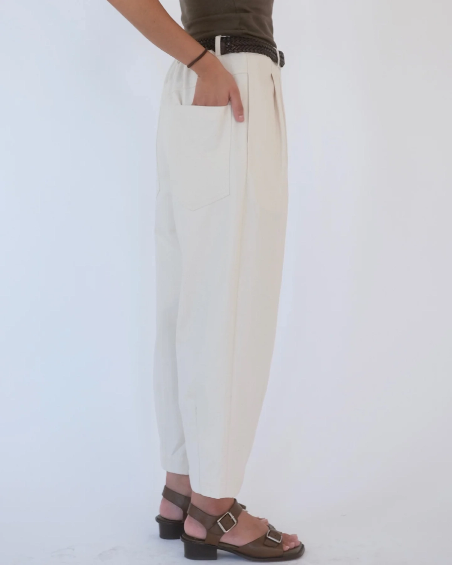 Model wearing the Shiloh Trouser by independent sustainable womenswear brand Studio Wylder, shot in an East London studio. For Spring, the updated Shiloh is cut in heavyweight ecru organic cotton denim, with a high-waisted, slouchy barrel leg, double pleated front, elasticated back waist, engineered belt loops and generous front and back pockets. Topstitching and bar tacks reinforce the pockets for longevity, while the subtle double-darted ankle helps shape the relaxed silhouette. Studio Iole worked as the creative pattern cutter, developing the fit and construction through fittings and manually grading the final pattern into multiple sizes for a more inclusive fit.
