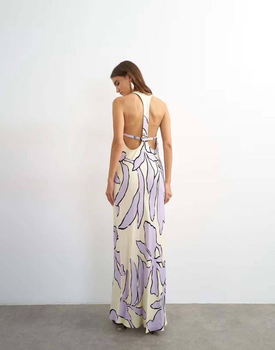 Model wearing the Satin Scoop Neck Maxi Dress by Topshop. The lilac and buttermilk floral satin dress is cut on the bias with a slim, fluid maxi silhouette that follows the body. The front features a scoop neckline with topstitched detailing and mini bra-style panelling, with a shaped bust seam adding structure through the bodice. The back is open and finished with a T-bar strap that crosses across the upper back. A hidden button fastening on the inside of the strap allows the dress to open for ease of dressing while keeping the back clean. The bias cut allows the soft satin fabric to fall naturally around the body, while the shaped seams and panelling give definition to the silhouette. Iole developed the pattern as the creative pattern cutter, working through the fit, bias cut, neckline, bust shaping and considered back fastening.