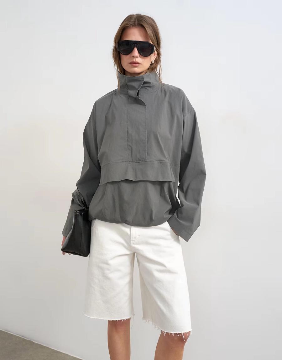 Model wearing the Technical Funnel Neck Jersey Track Top by Topshop in a stylised fashion shoot. The slate grey jacket is shown as a full front view highlighting the structured funnel neck, concealed front placket and relaxed shape. The model wears oversized black ski-inspired sunglasses, adding a bold fashion-led styling element to the contemporary sportswear-inspired design. The funnel neck is the main focus of the image, showing the shape and construction of the collar in detail. Iole worked as the creative pattern cutter, developing the jacket pattern and refining the proportions and construction of the funnel neck, placket and overall silhouette.