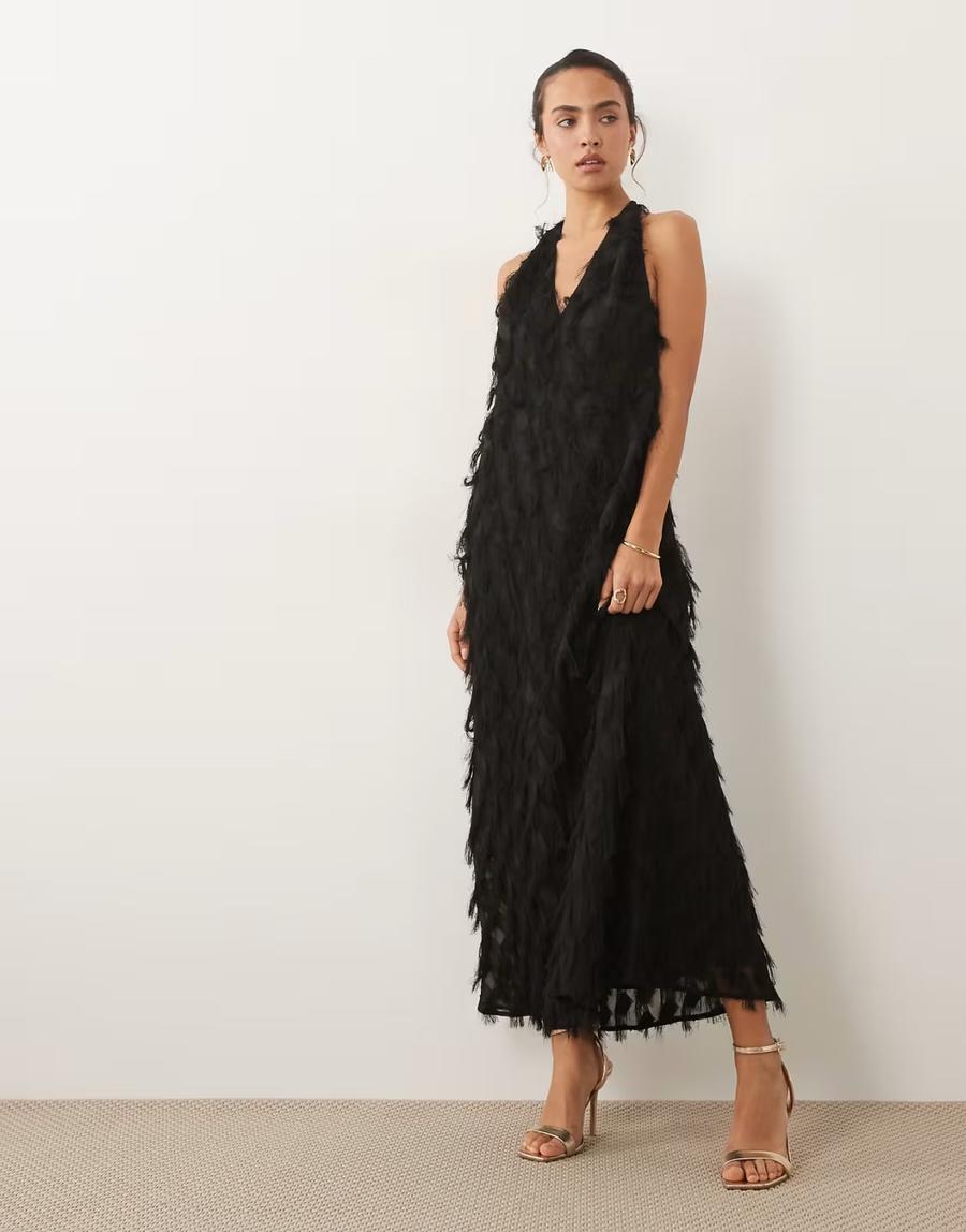 Model wearing the textured fringe plunge backless halter maxi dress by ASOS Design, photographed in a studio setting. The contemporary eveningwear dress features a plunge halterneck, fitted silhouette and open back, creating an elongated and striking maxi shape. Textured fringe detailing covers the dress, adding movement and dimension across the silhouette. The plunge neckline and backless construction create a strong contrast between the more covered front and exposed back. Iole developed the digital pattern as the creative pattern cutter, working through the fit, proportions, plunge halterneck and open back to create the intended silhouette. 