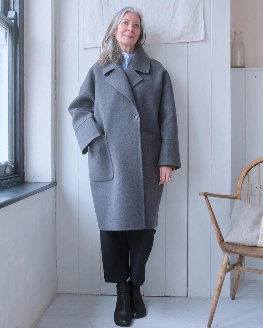 Model wearing an oversized grey wool overcoat by independent sustainable womenswear brand Studio Wylder. The tailored coat features a relaxed cocoon silhouette, wide notched lapels, dropped shoulders and large front patch pockets, balancing an oversized fit with considered tailoring and structured construction. Studio Iole worked as the freelance pattern cutter, developing the creative pattern through fittings and refinements and working closely on the fit, silhouette and construction through to the final sealed production pattern used to produce the finished garment shown.
