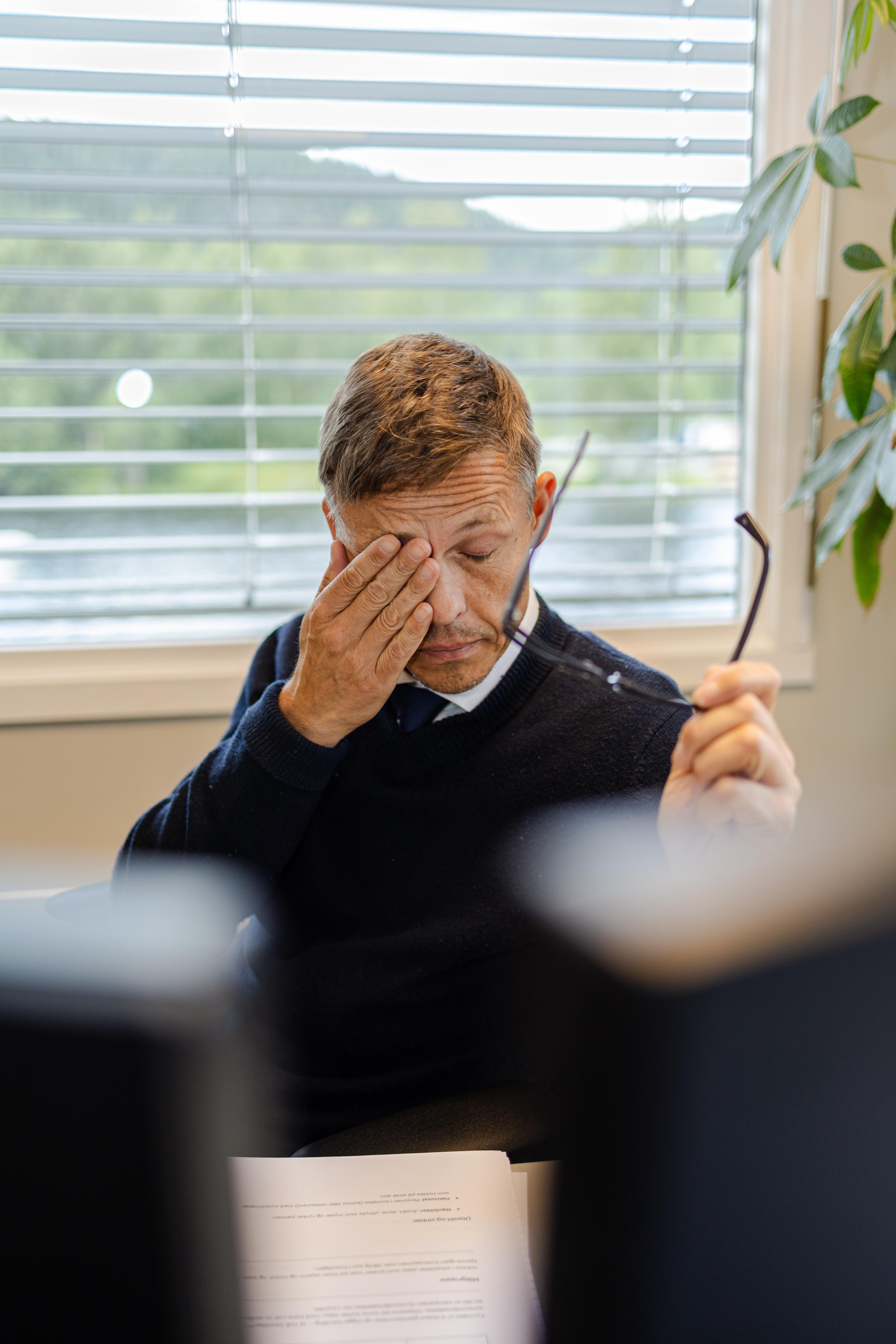 Mann som gnir seg i øynene foran skjermen