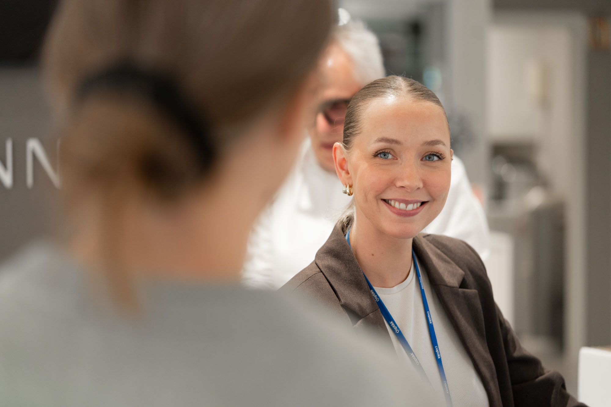 Optiker hos c)optikk Revetal smiler til en kunde ved skranken