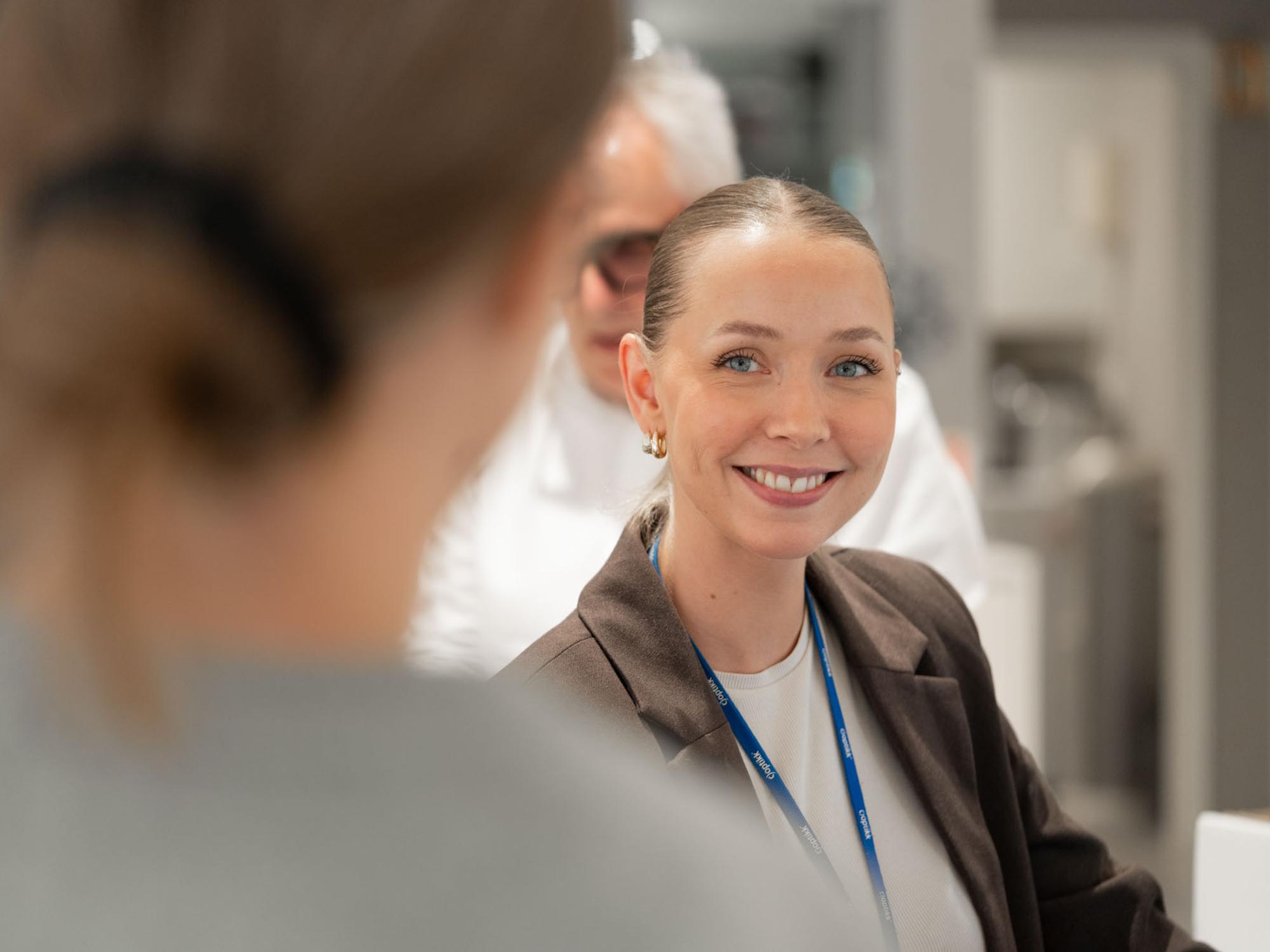 Optiker hos c)optikk Revetal smiler til en kunde ved skranken