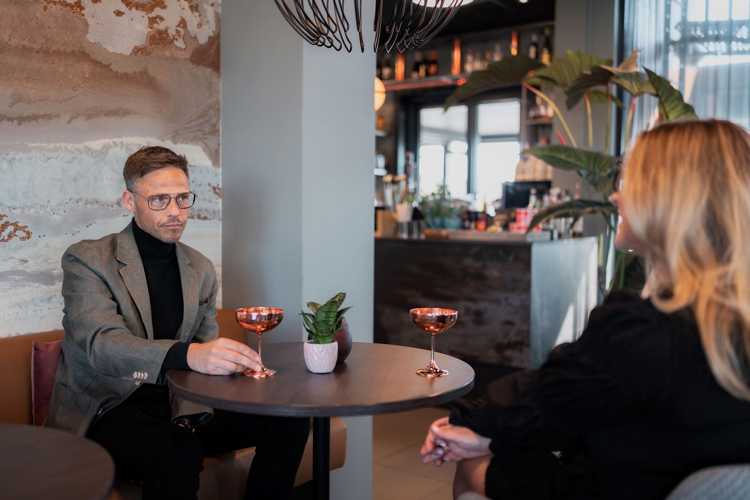Par med briller tar en drink i baren