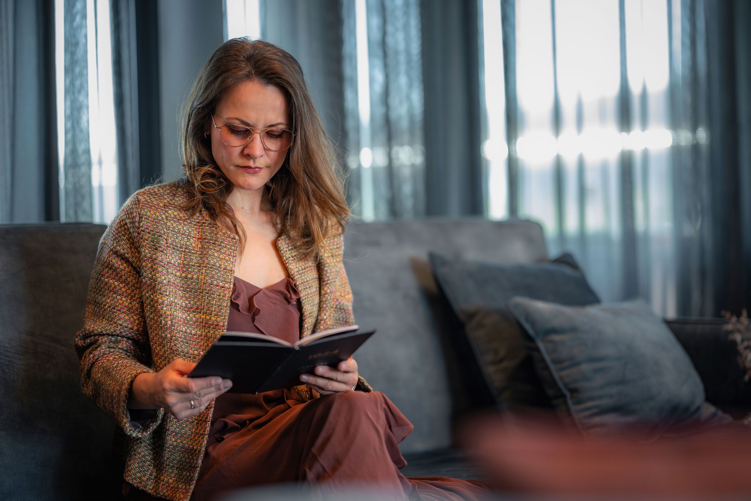 Kvinne med briller leser i sofaen