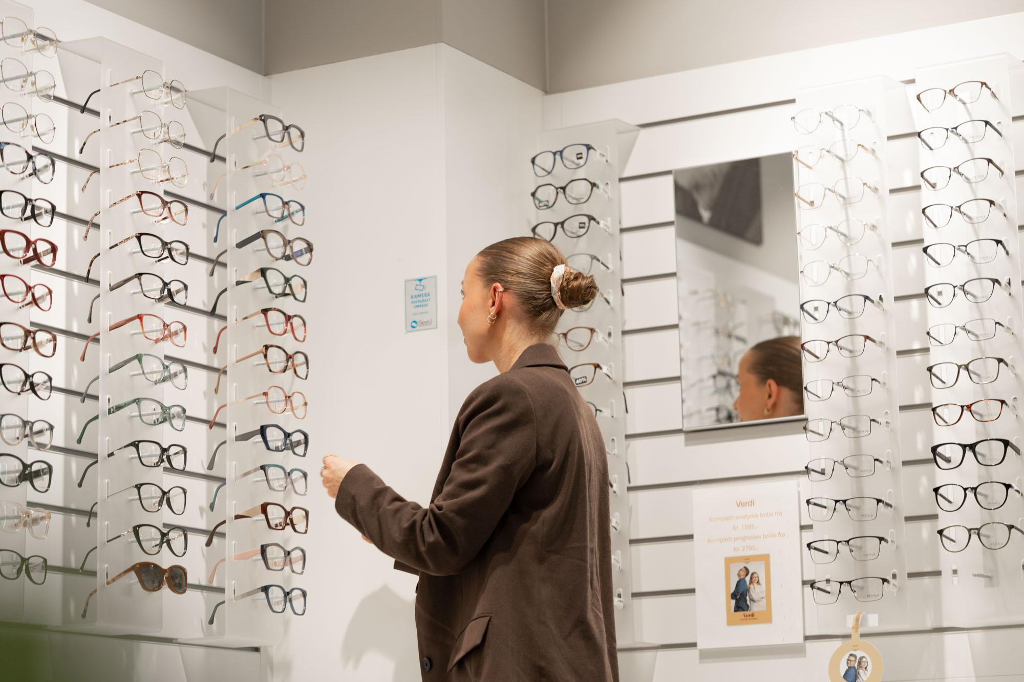 Optiker ved brilleveggen med innfatninger hos c)optikk Revetal