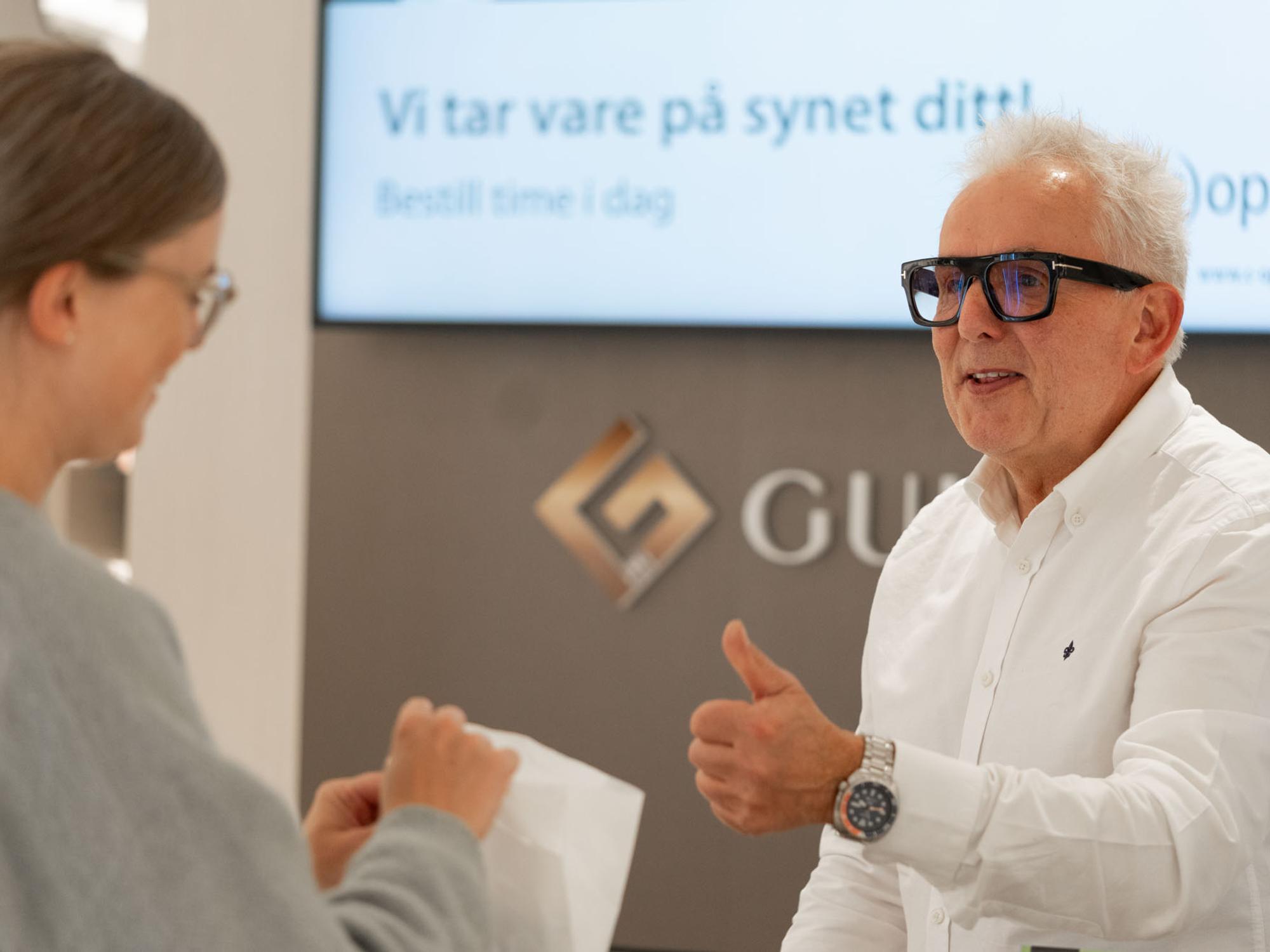 Fornøyd kunde får brillene sine ved skranken hos c)optikk Revetal