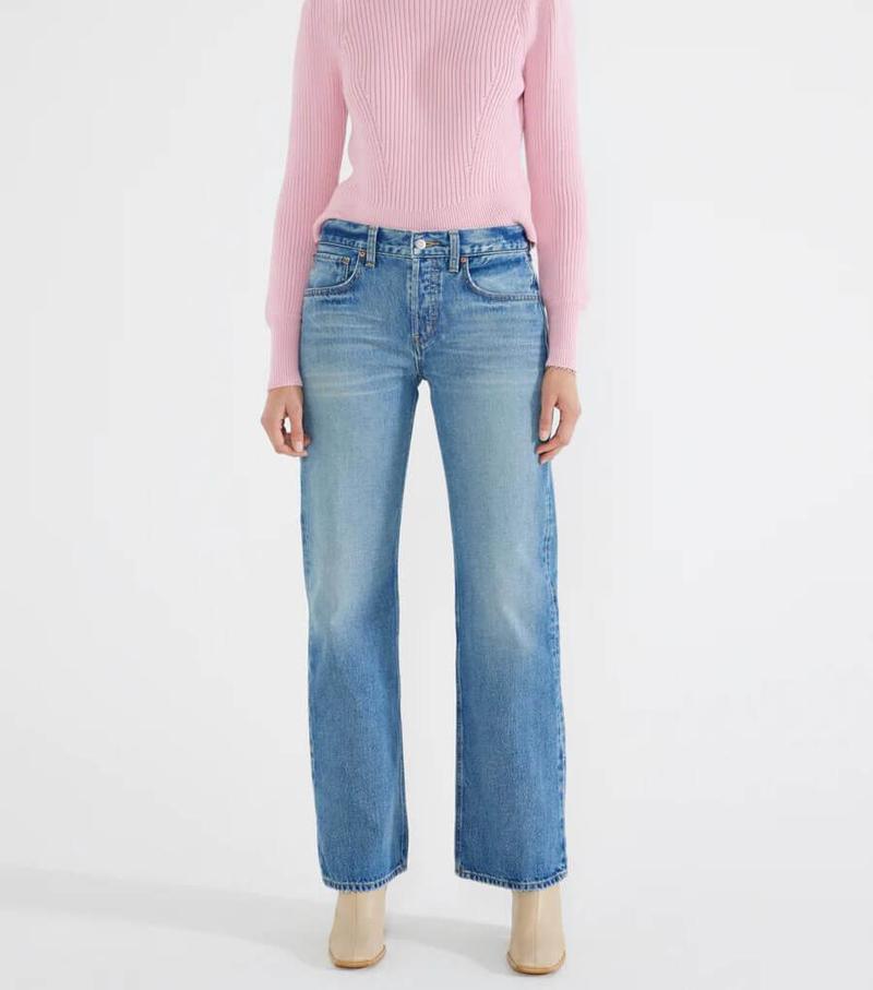 A woman in pink sweater and pair of etica jeans.