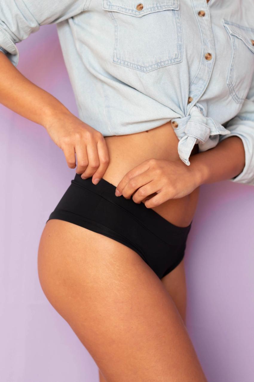 Woman's torso, wearing denim top and black pair of underwear.