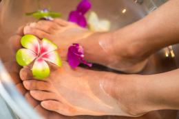 Feet in a silver basin filled with water and flowers