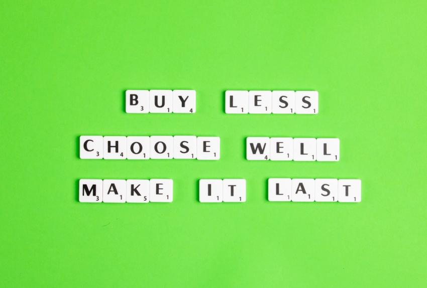White Scrabble letters "Buy less, choose well, make it last" on ground background