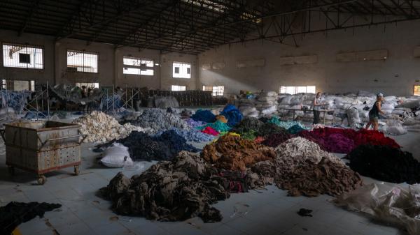 Piles of dyed fabrics on the ground of an old, dark factory.