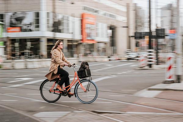 A professional woman riding her orange bike to work in the city.