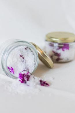Bath salts with violet flowers mixed in the glass jar.