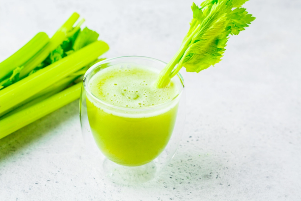 Celery juice in a glass with a stalk in it.