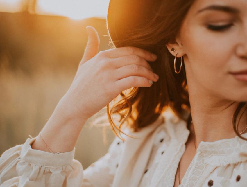 woman pulling hair back to display her brass hoop earring