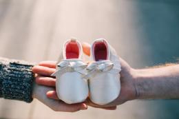 White baby shoes on mom and dad's hands.