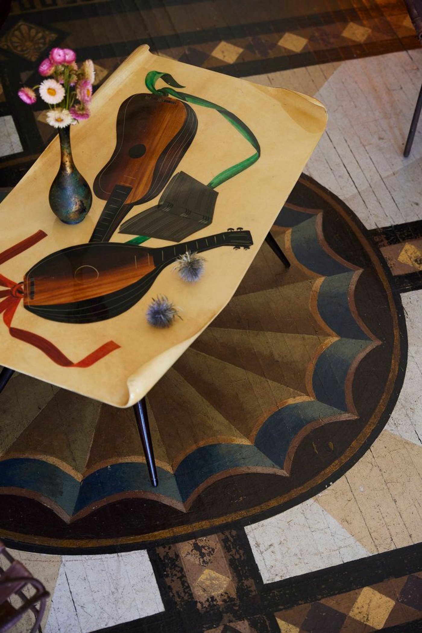 Two lutes and a vase of flowers laid on a painted round table.