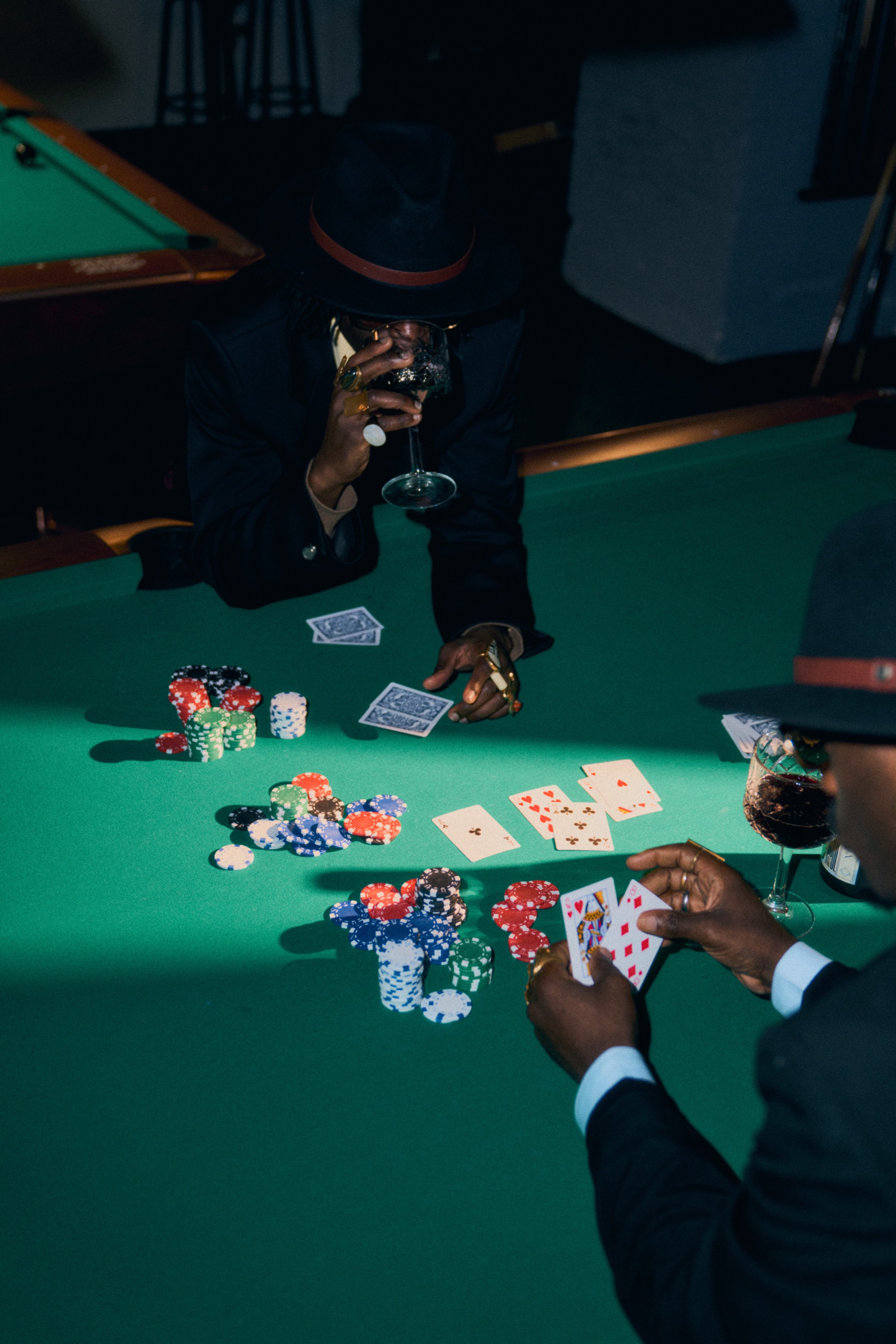 Players lean over a green poker table covered in chips and cards.