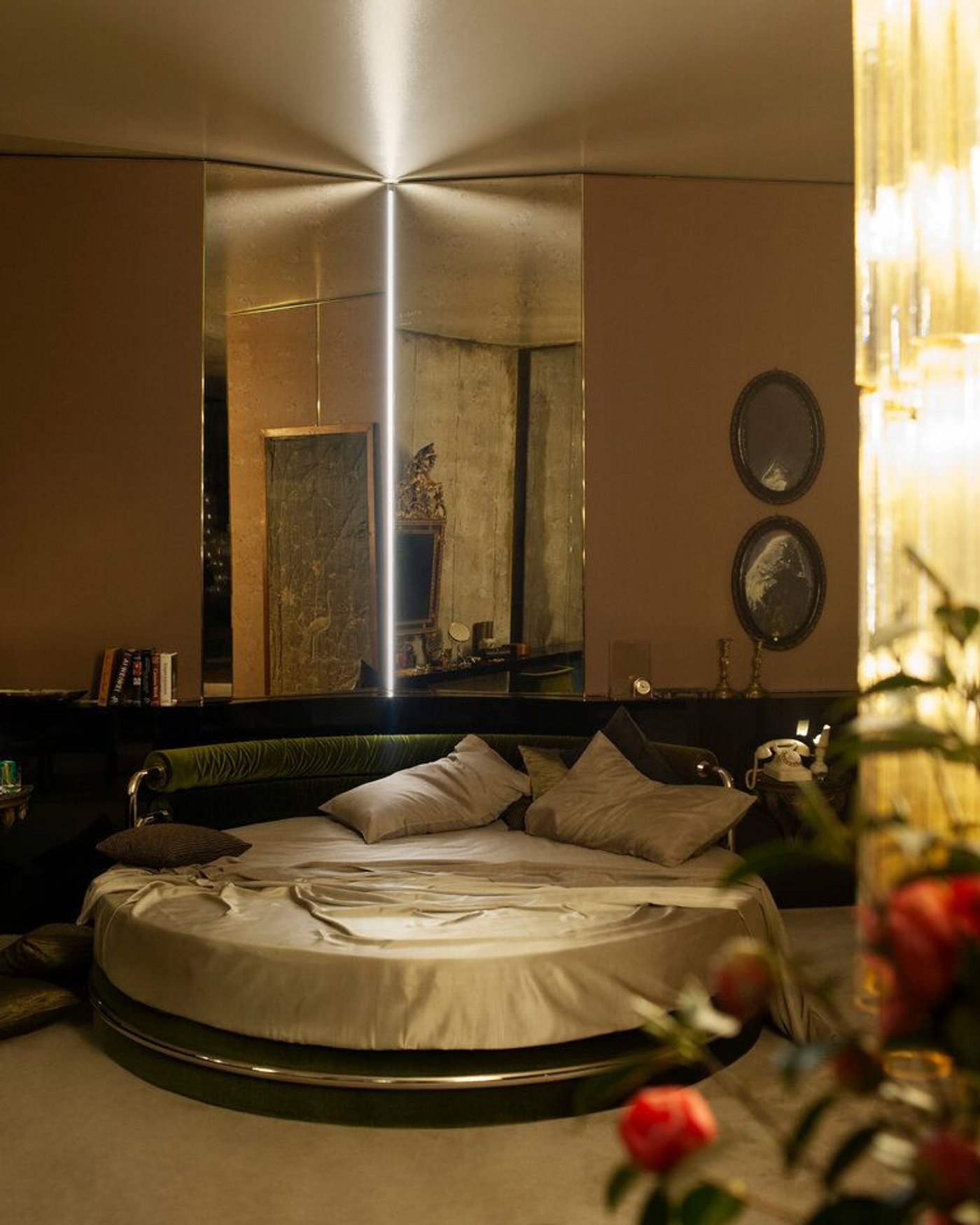 A round bed in a brown bedroom, with mirrored walls behind it.