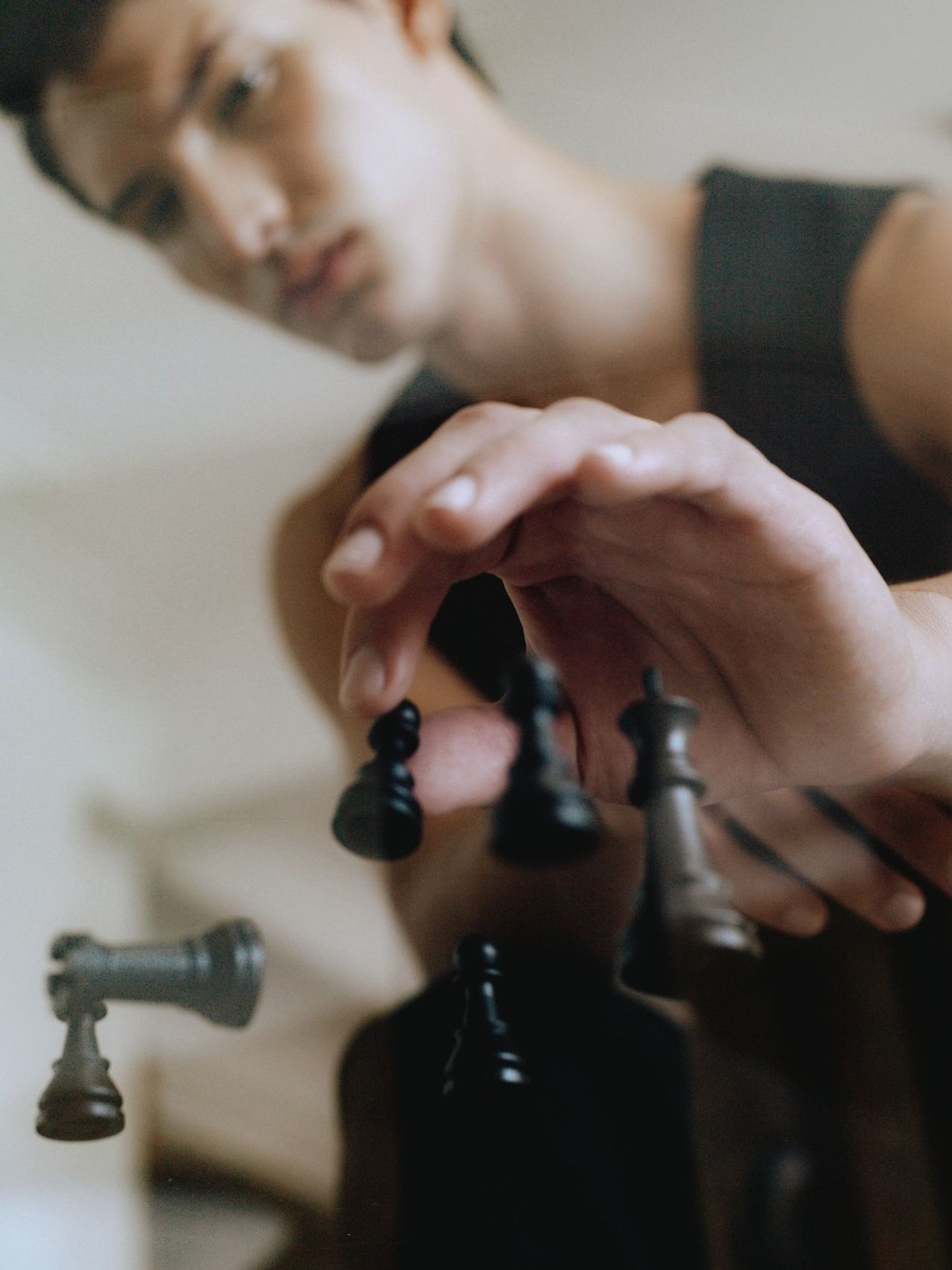 A man reaches across a chessboard to move a black piece.