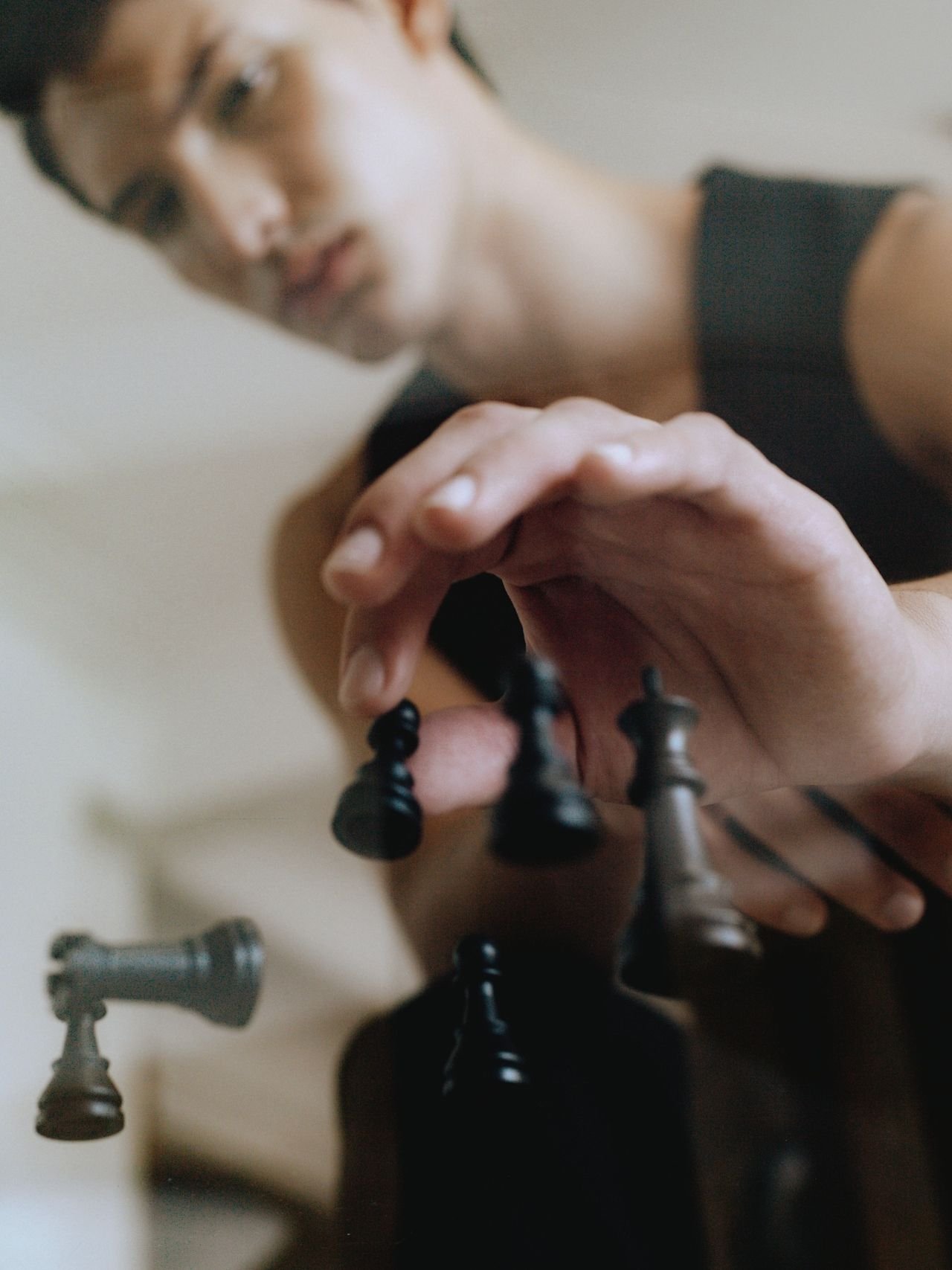 A man reaches across a chessboard to move a black piece.
