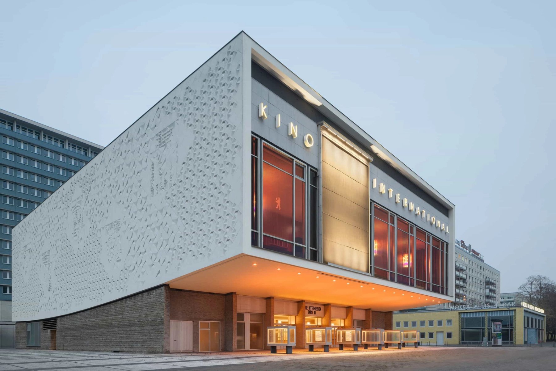 The Kino International cinema in Berlin, its white relief facade lit at dusk.