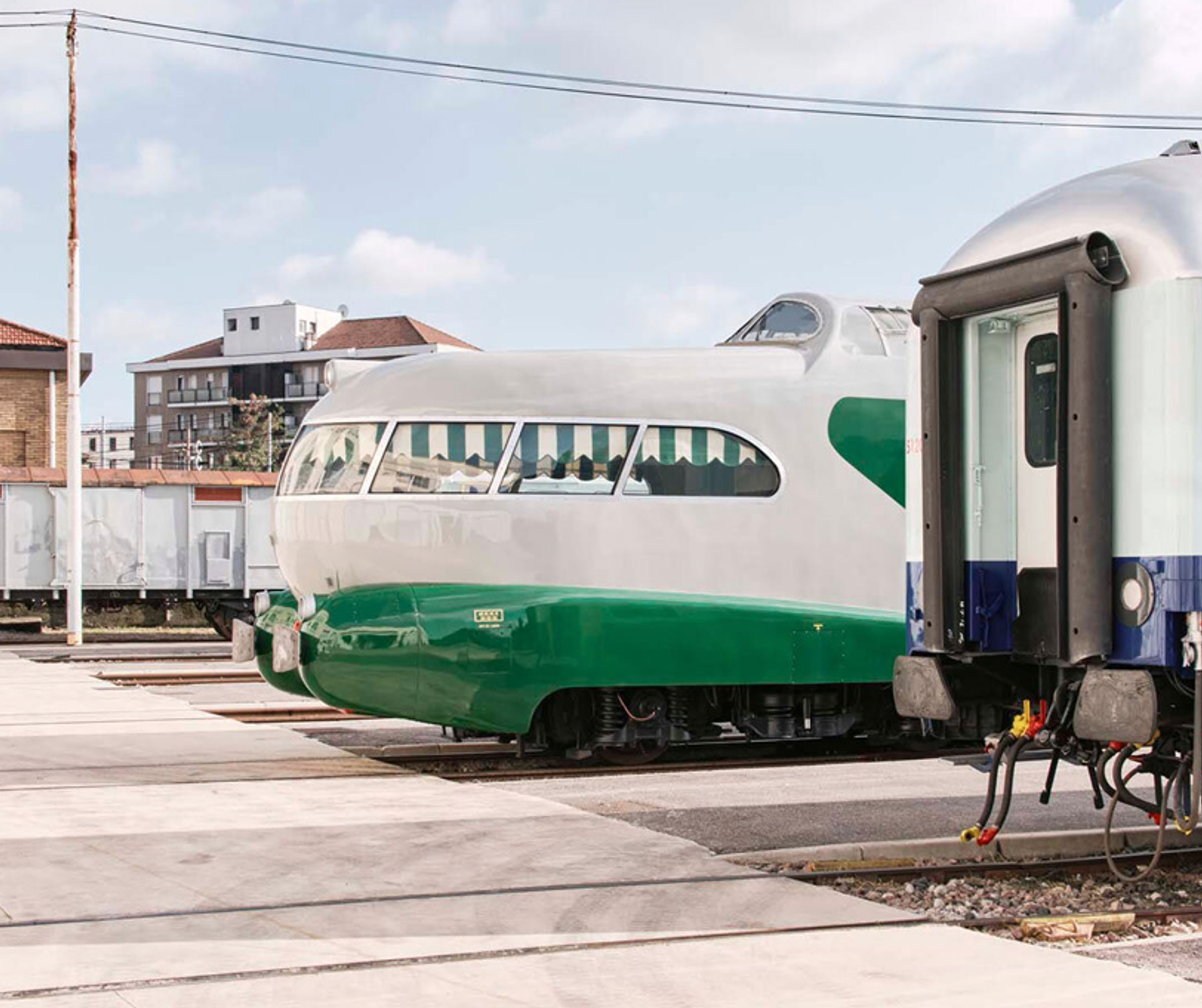 A streamlined green and white train standing in a depot.