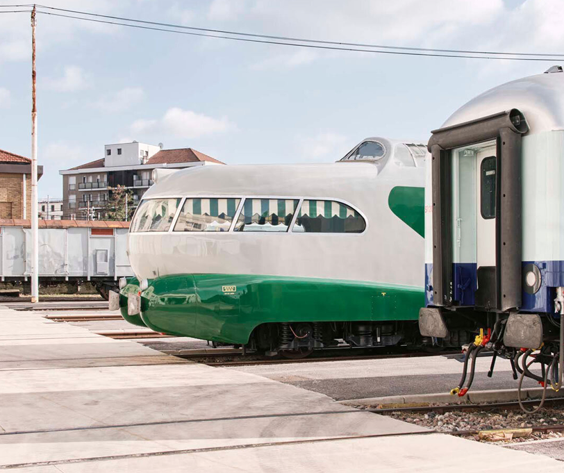 A streamlined green and white train standing in a depot.