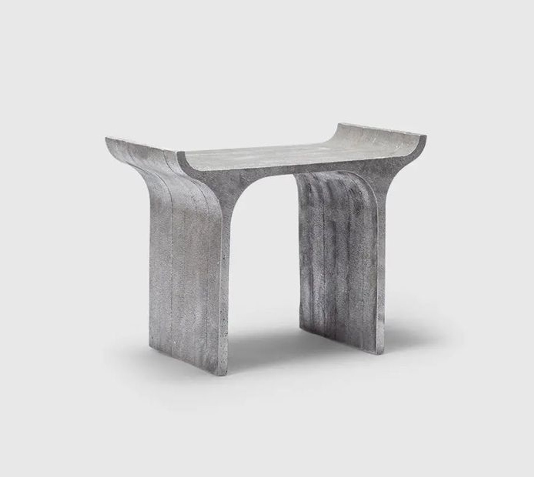 A grey stone bench with curved ends, on a plain background.