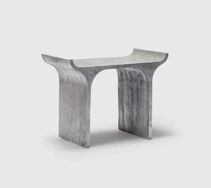 A grey stone bench with curved ends, on a plain background.