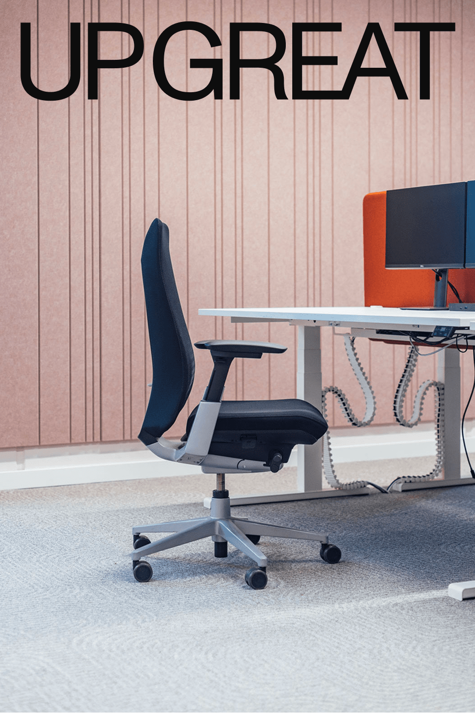 An office chair at a white desk in front of a pink panelled wall, under the UP GREAT name.