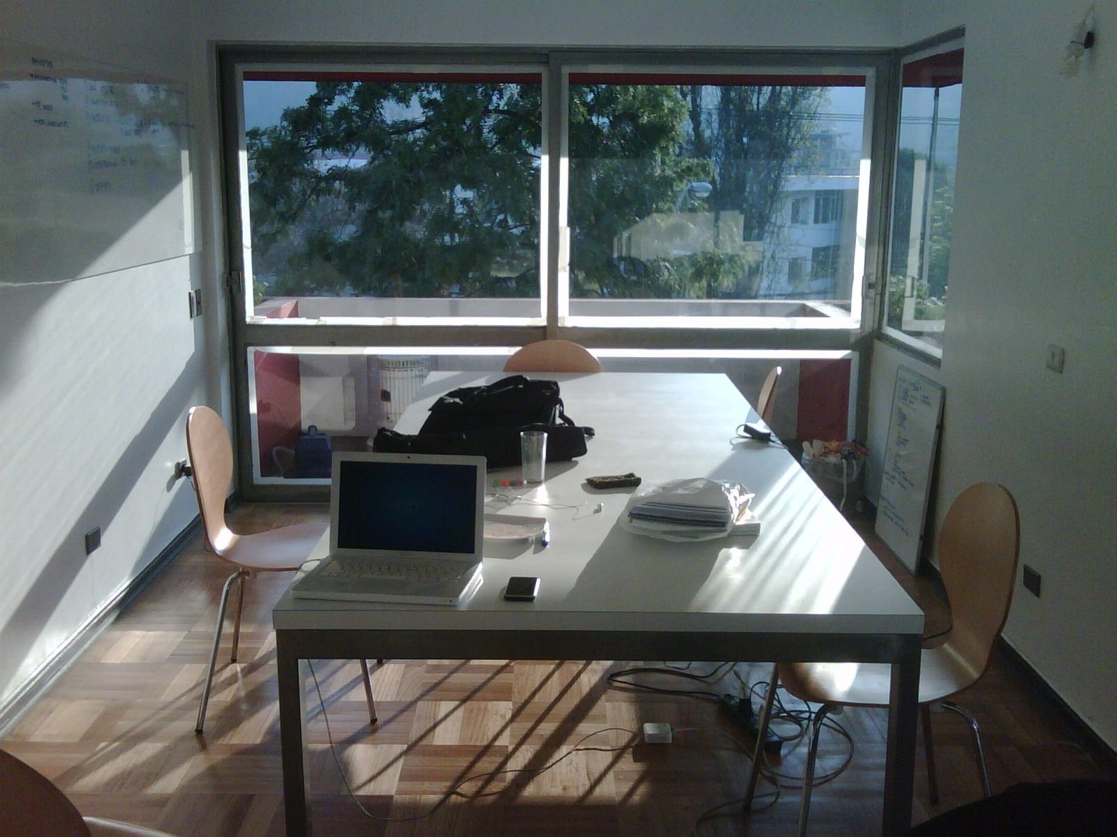 A studio with a long white table, a laptop on it and windows along the wall.