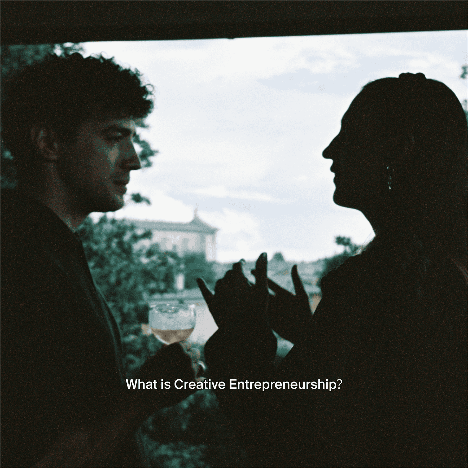 Two people talk by a window, with the question what is creative entrepreneurship under them.