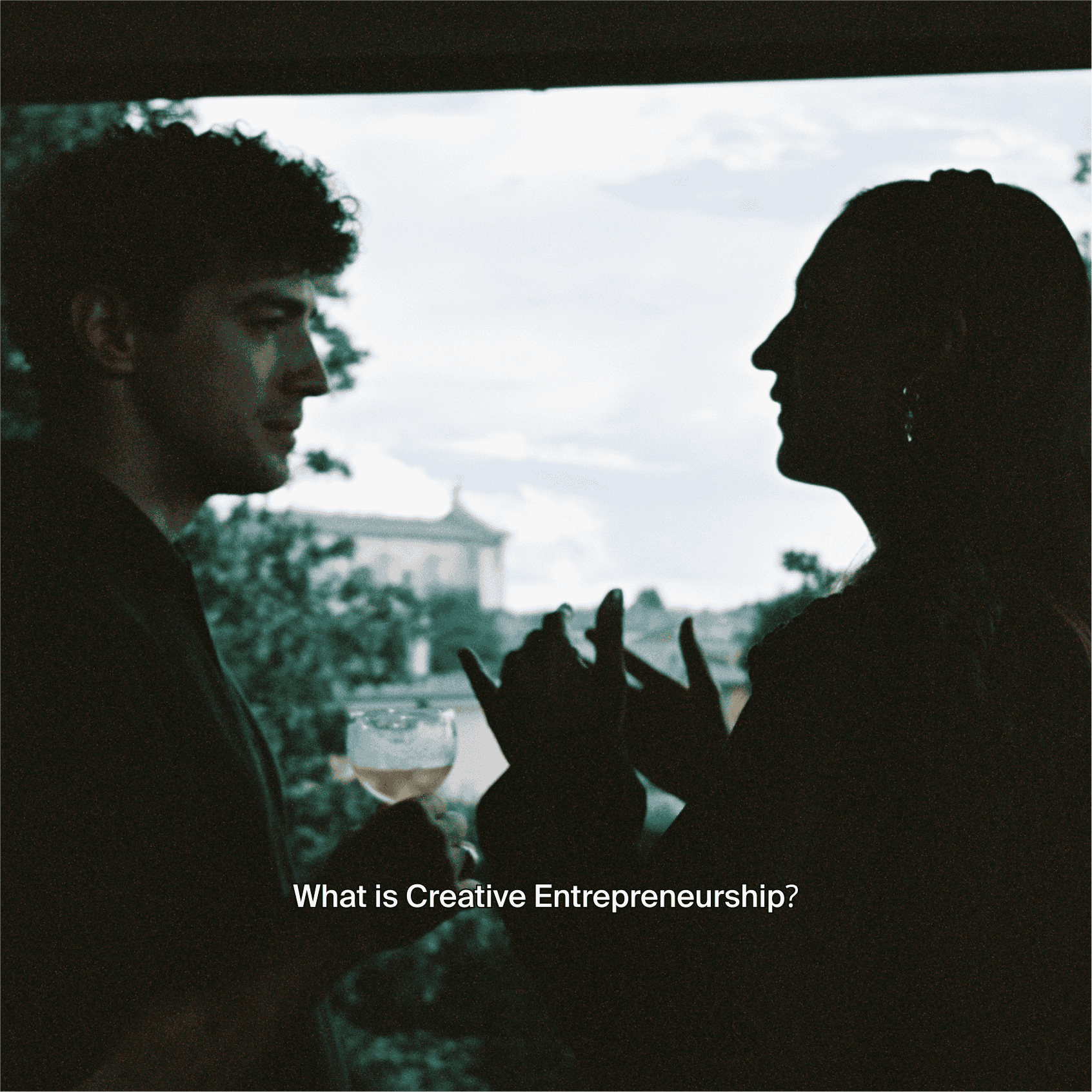 Two people talk by a window, with the question what is creative entrepreneurship under them.
