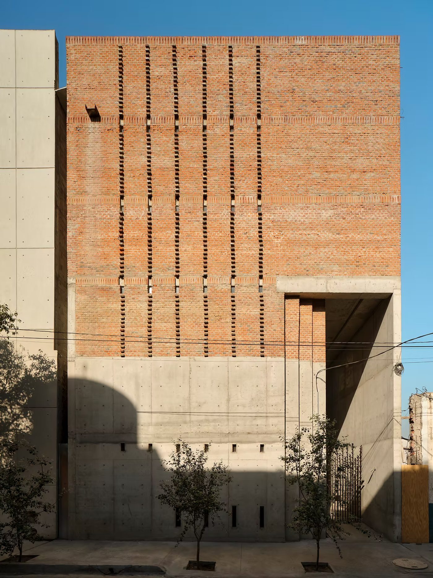 A brick and concrete building on a street corner, with slotted openings in the brickwork.